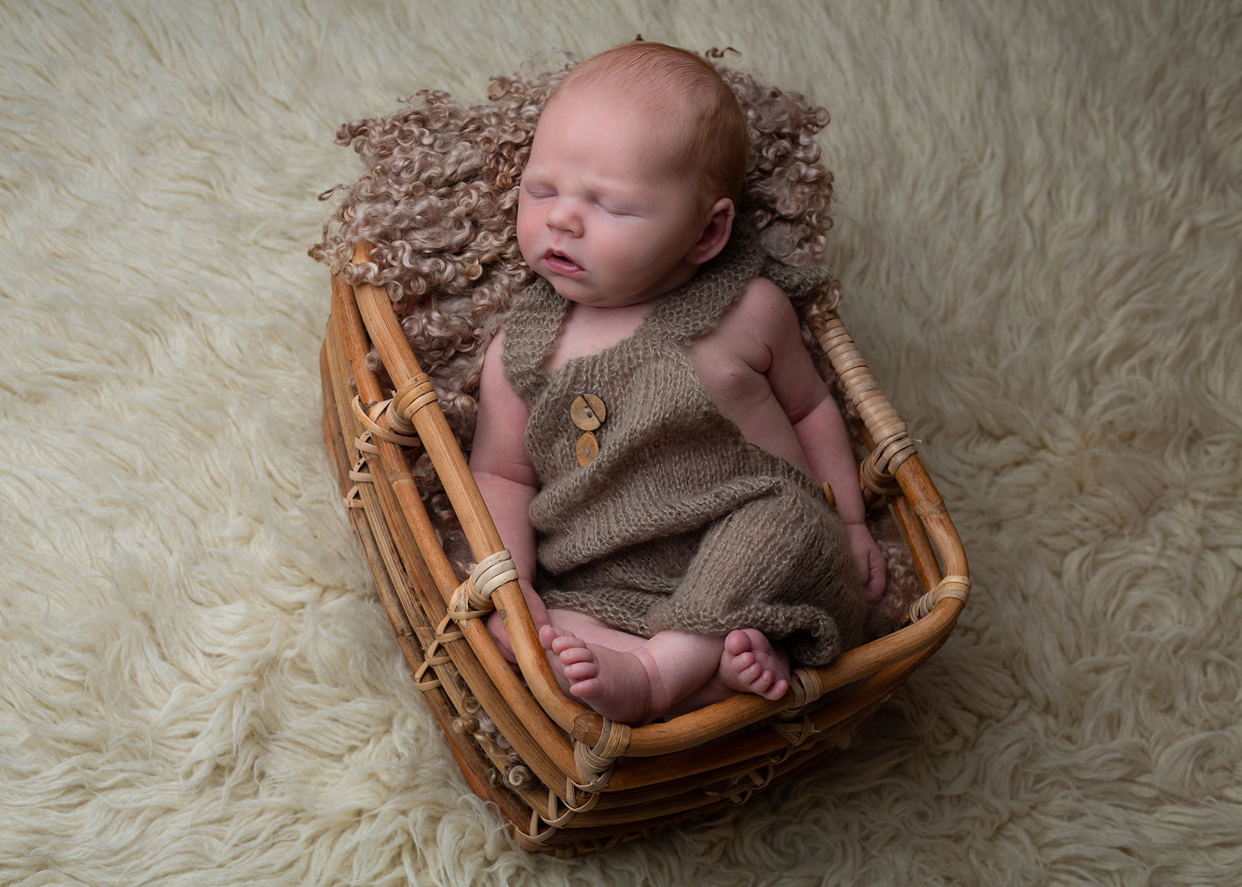 Baby boy sleeping in a wicker basket, captured by Ceris Hicks Photography