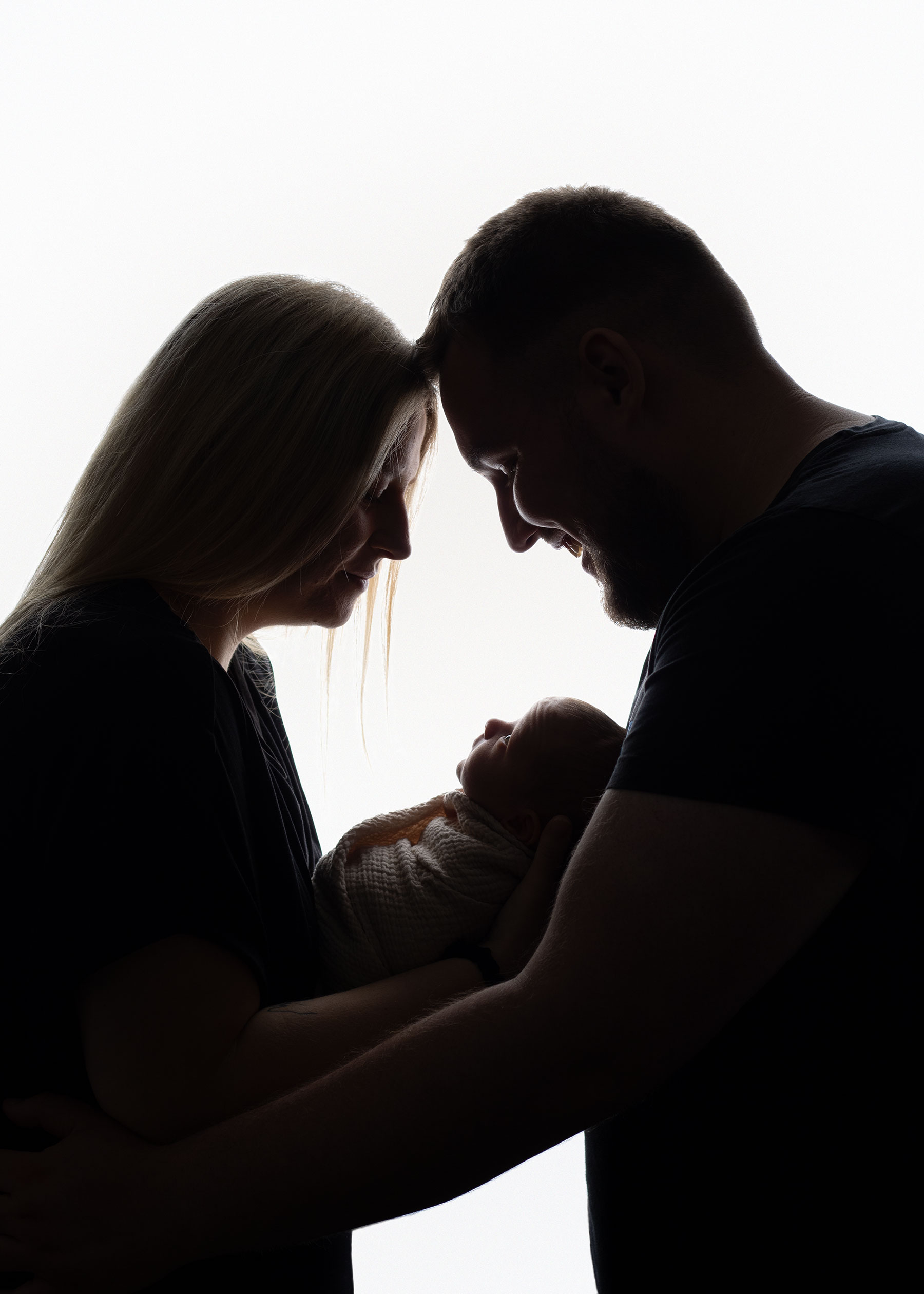 Mother and father holding their newborn baby, captured in their own home
