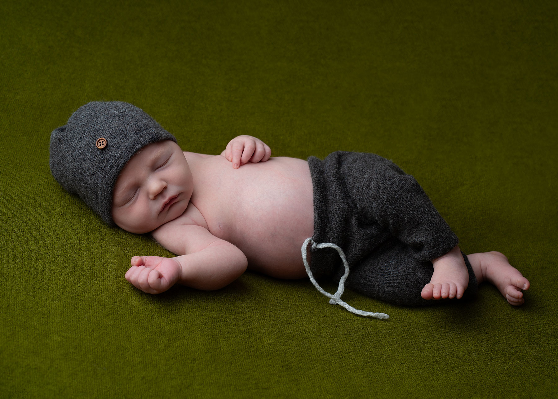 Baby boy in a grey hat with matching trousers, captured by Ceris Hicks Photography