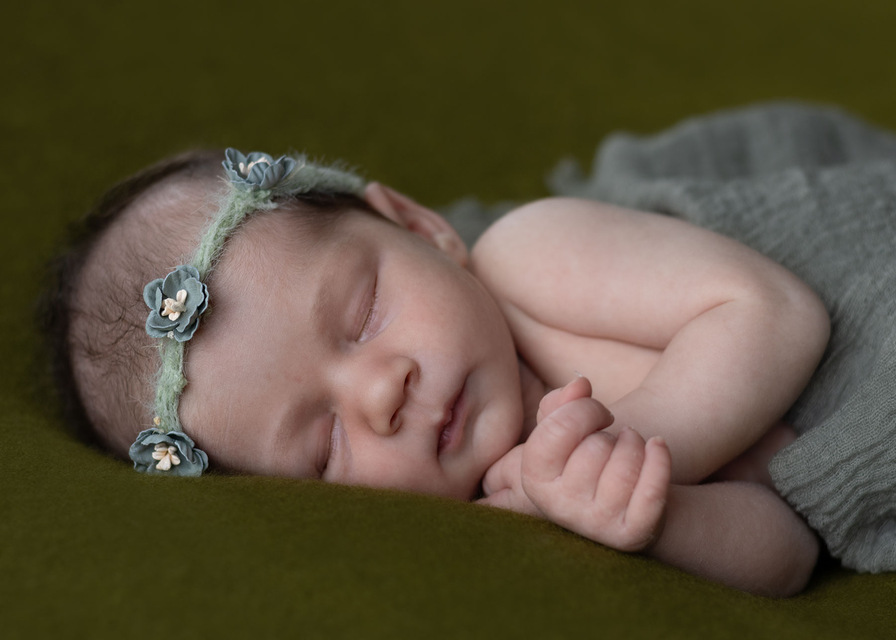 Baby girl wearing a green headband during a newborn photoshoot