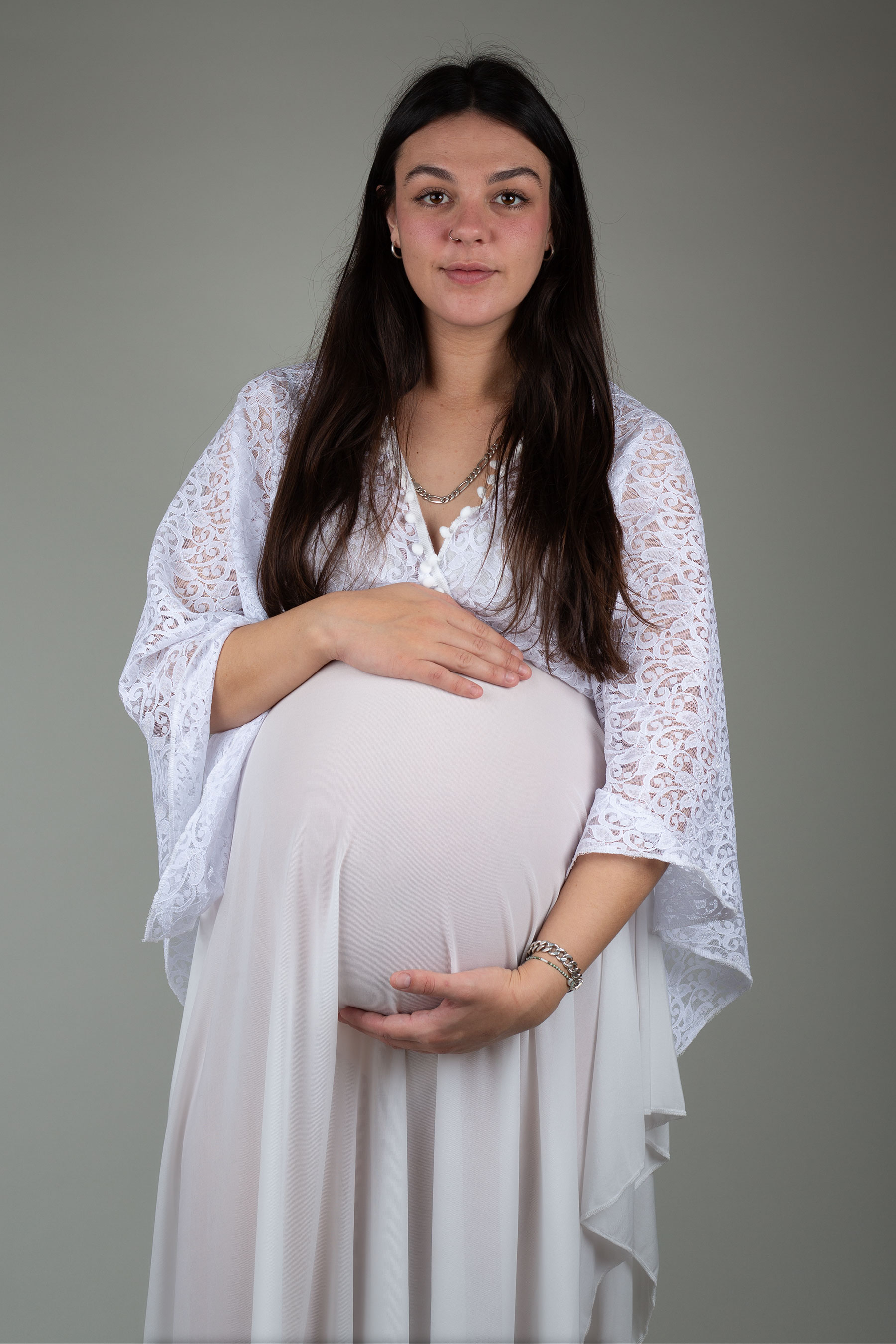 Mother-to-be looking at the camera whilst holding her baby bump